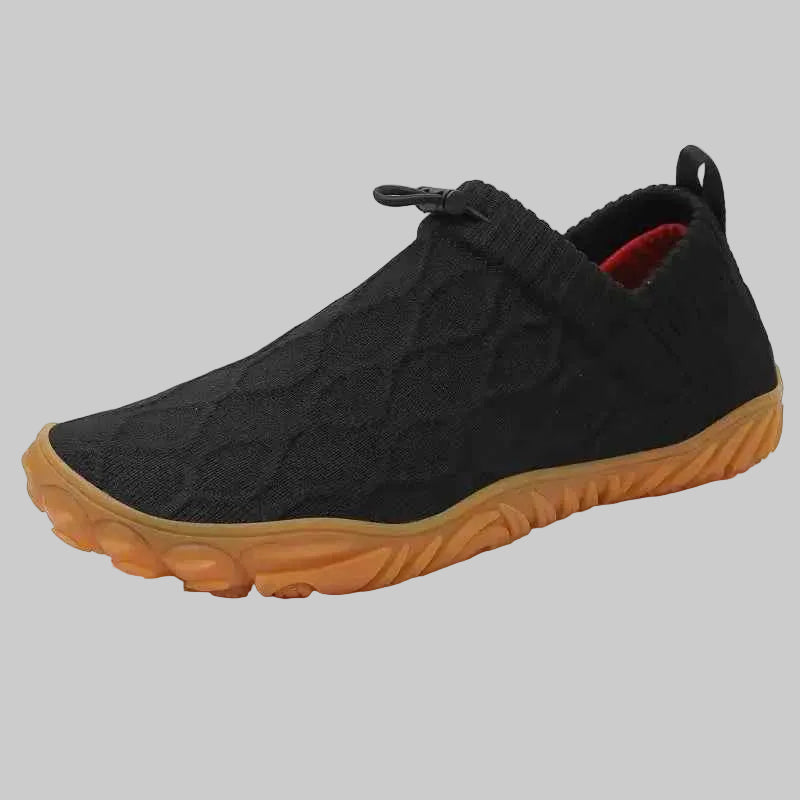 Black slip-on shoe with a brown sole on a white background