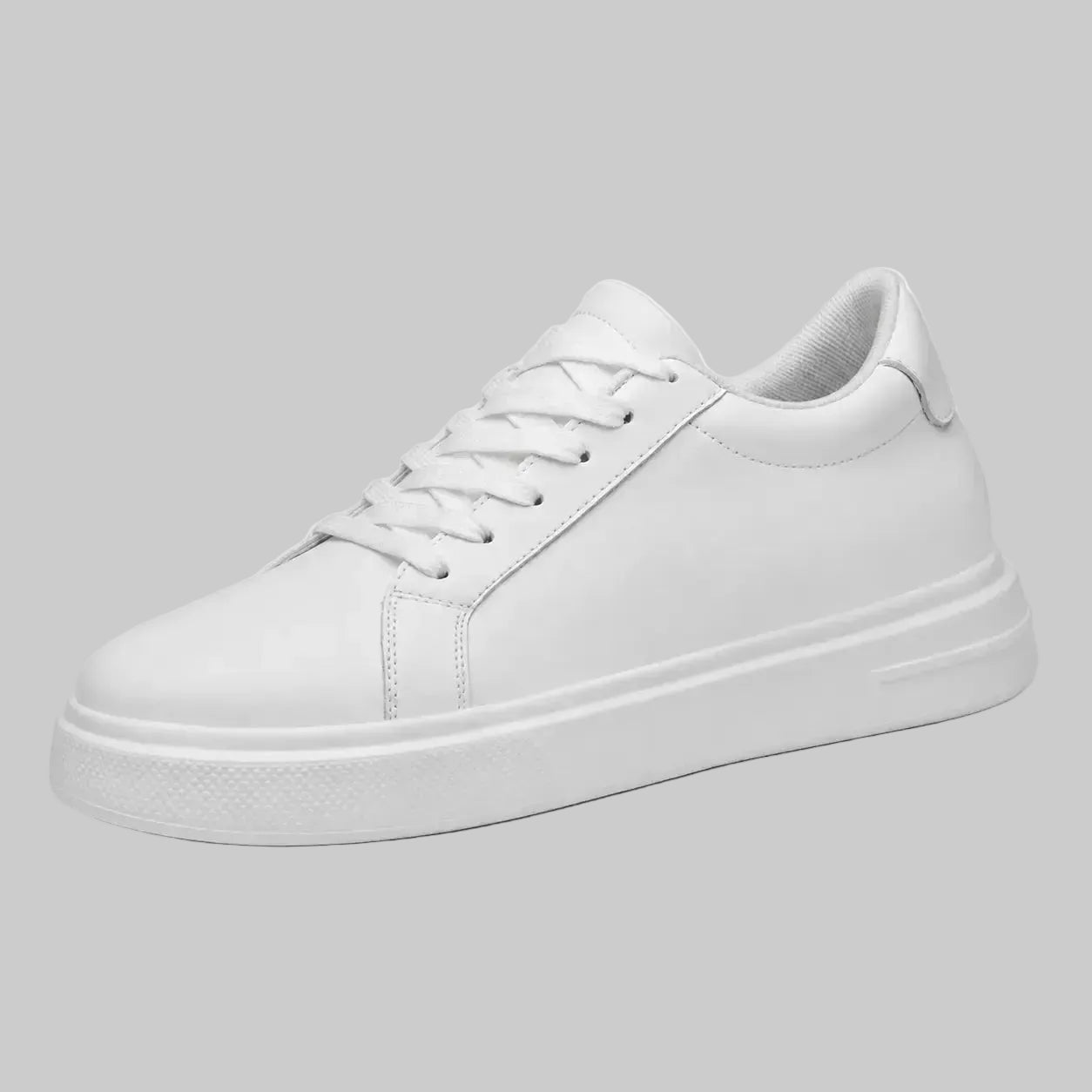 A clean white low-top sneaker with white laces and a thick white platform sole, shown from a three-quarters angle against a solid gray background.