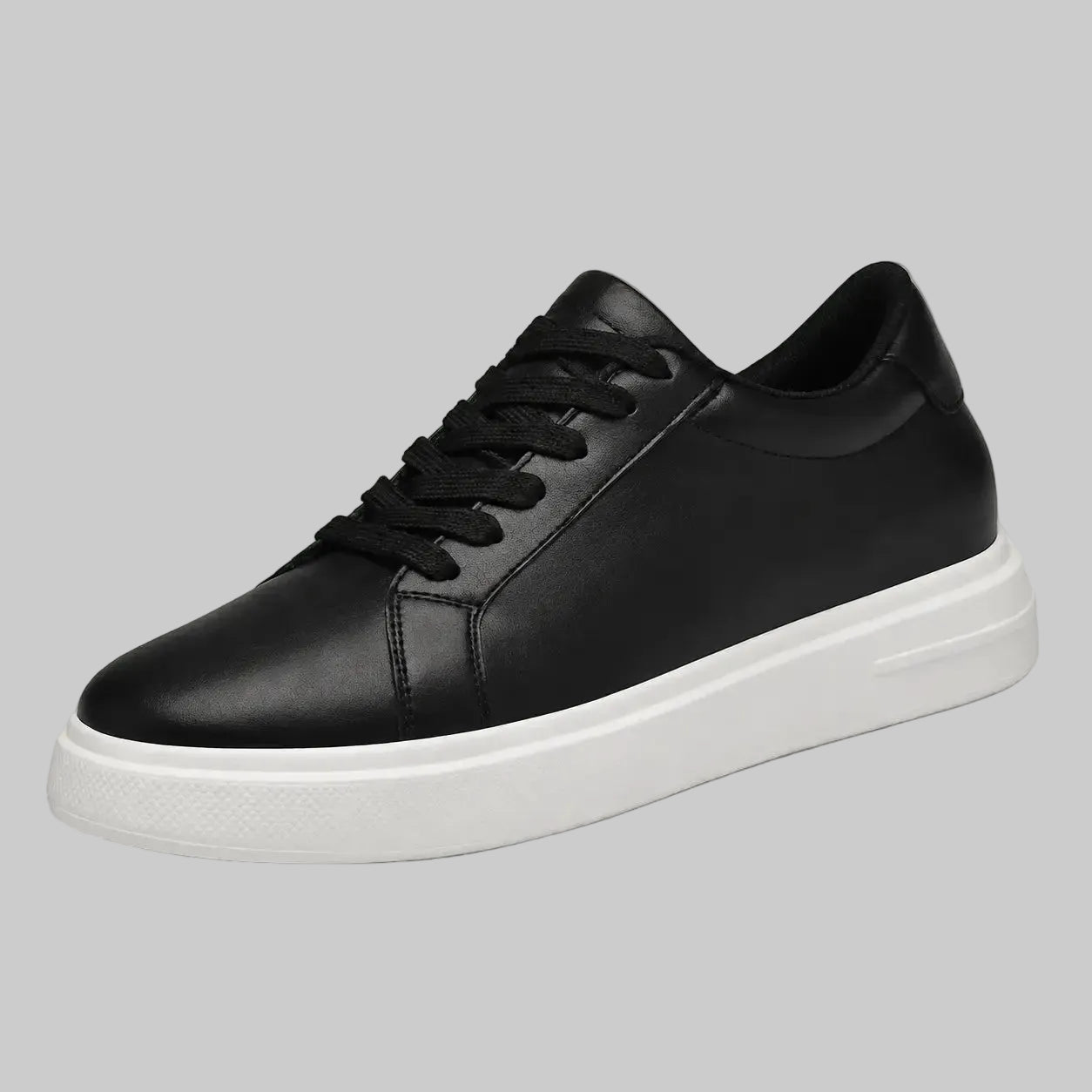A black leather low-top sneaker with black laces and a thick white platform sole, shown from a three-quarters angle against a solid gray background.