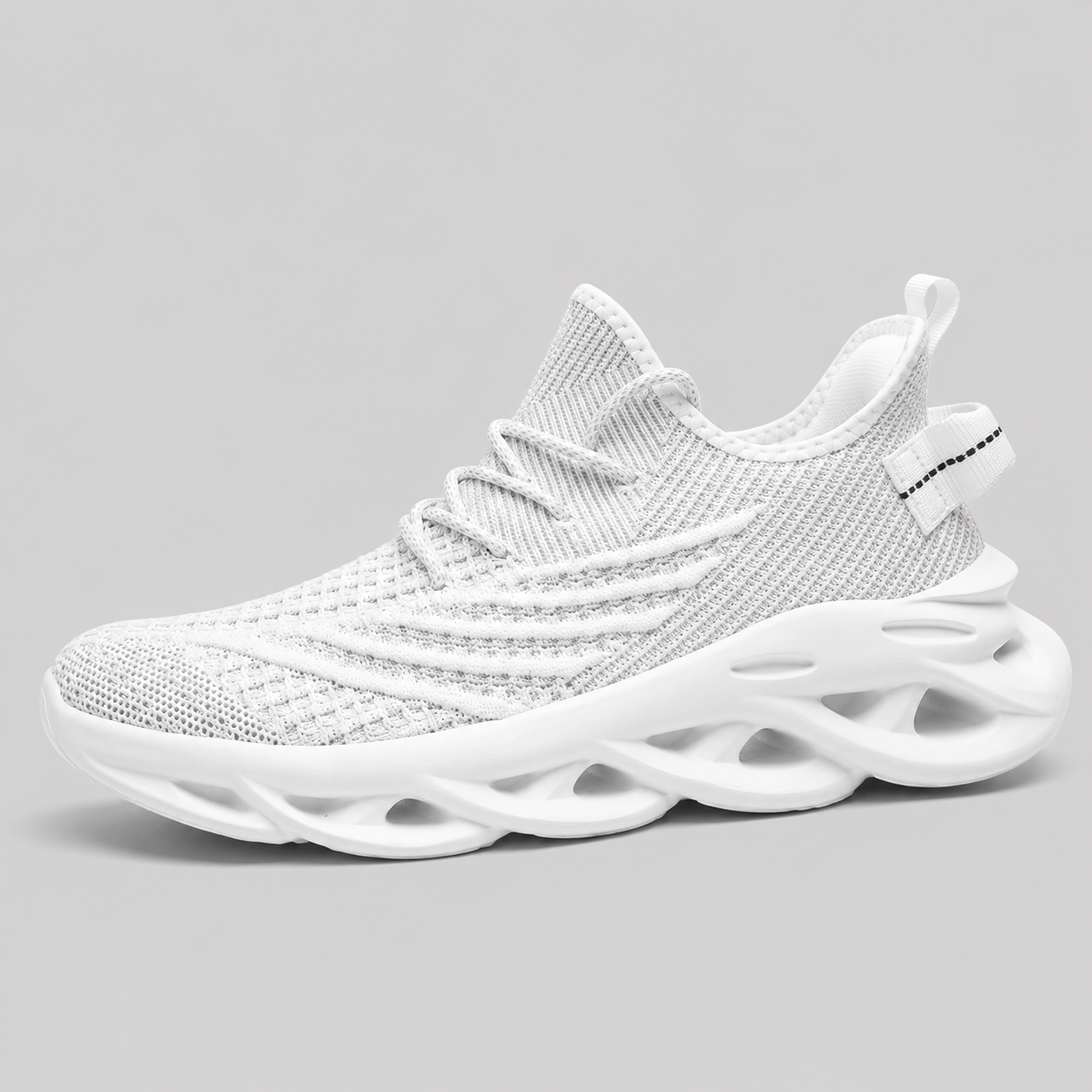 A white knit athletic sneaker with a chunky, sculpted wavy sole, shown from a side profile on a neutral gray background.